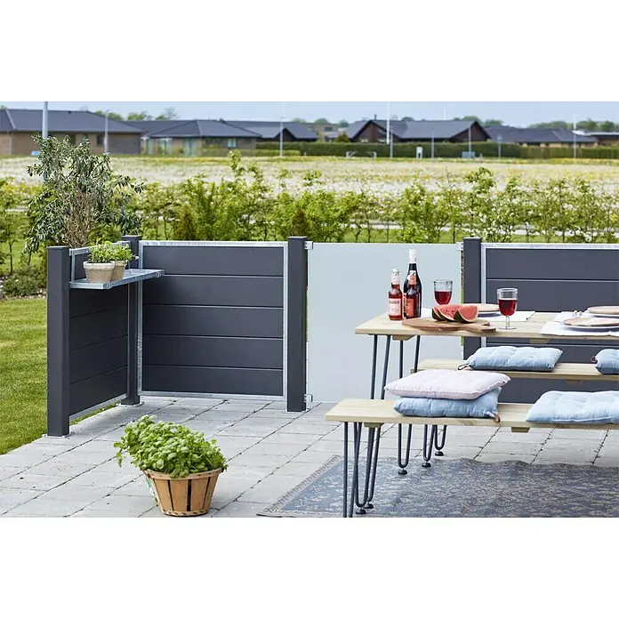 Plus Sichtschutzelement Futura - 90 x 91 cm, Glas, Matt satiniert - Das Bild zeigt einen stilvollen grauen Sichtschutzzaun aus Holz mit integriertem Regal und einer gemütlichen Gartensitzgruppe.
