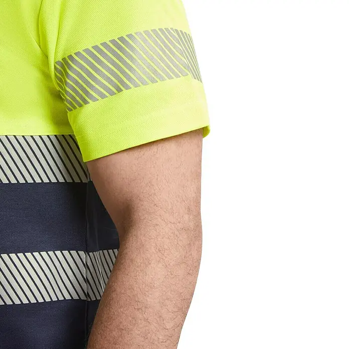 Camiseta alta visibilidad Tauri - XXXL, Amarillo/Azul - Primer plano de un polo amarillo y azul marino de alta visibilidad con rayas reflectantes en la manga y el cuerpo.