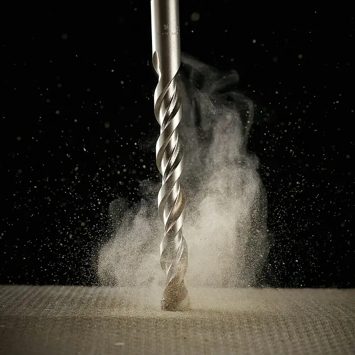 DeWalt Broca para hormigón y mampostería DT6671-XJ - 1 ud., Diámetro de la broca: 4 mm - Primer plano de una broca helicoidal perforando un material, con polvo y pequeñas partículas arremolinándose en el aire.