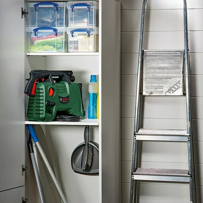Bosch Hochdruckreiniger EasyAquatak 120 - 1.500 W - Ein Blick in einen Putzschrank mit dem Bosch Hochdruckreiniger Aquatak 33-11, Putzutensilien und durchsichtigen Aufbewahrungsboxen.