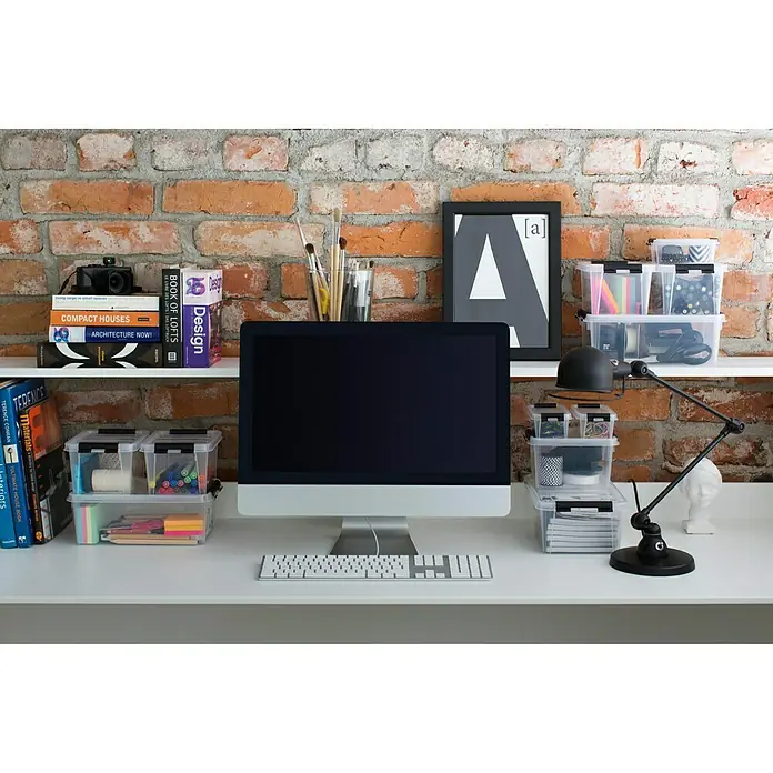 SmartStore Aufbewahrungsbox Classic 1,5 - L x B x H: 20 x 15 x 11 cm, Kunststoff, Transparent - Ein ordentlicher Schreibtisch mit Aufbewahrungsboxen, Büchern und einem Computermonitor vor einer Backsteinmauer.