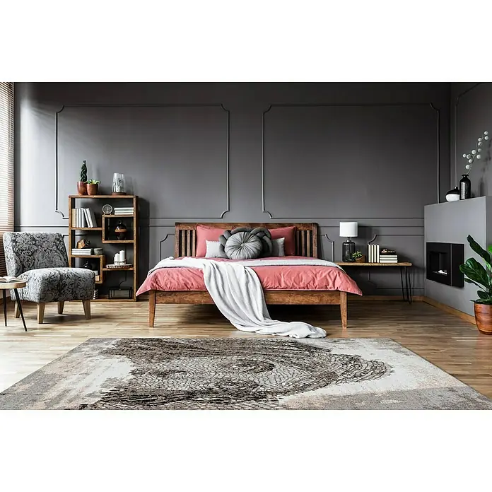 Kayoom Kurzflorteppich Iglesia - Taupe, 150 x 80 cm, 100 % Polyester - Zimmeransicht mit einem großen gemusterten Teppich im Vordergrund, einem Bett in der Mitte und einem Stuhl und Bücherregal an der Seite.