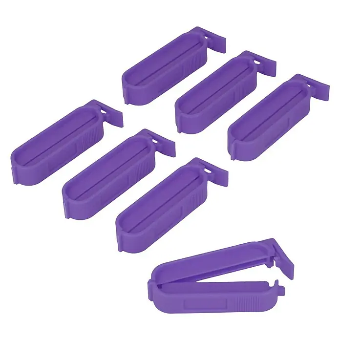 Metaltex Clips - 7 Stk., L x B x H: 6 x 1,2 x 1,2 cm - Eine Nahaufnahme von sieben lila Tütenverschlüssen, sechs davon geschlossen und einer offen.