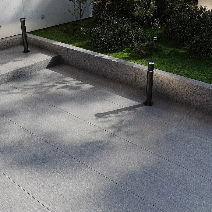 Terrassenplatte - 40 x 60 x 3 cm, Titangrau, Granit - Außenaufnahme eines stilvollen, modernen Gartens mit linearen grauen Fliesen und schlanken schwarzen Wegeleuchten.