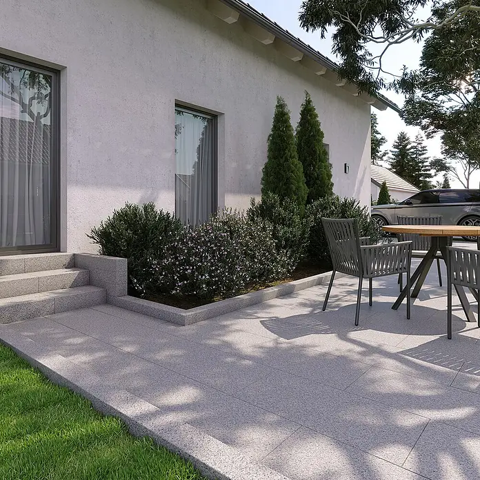 Granitstufe G 603 - Grau, 50 x 33 x 15 cm - Außenansicht eines modernen Hauses mit Terrasse, Gartenmöbeln und gepflegten Pflanzen. Das Design ist schlicht und elegant.