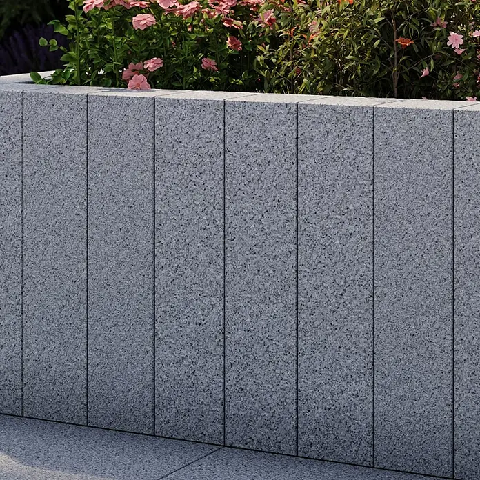 Palisade G 603 - 50 x 12 x 12 cm, Grau - Nahaufnahme einer grauen Blocksteinmauer mit Blumen bepflanzt, die im Außenbereich eine moderne und stilvolle Note verleiht.