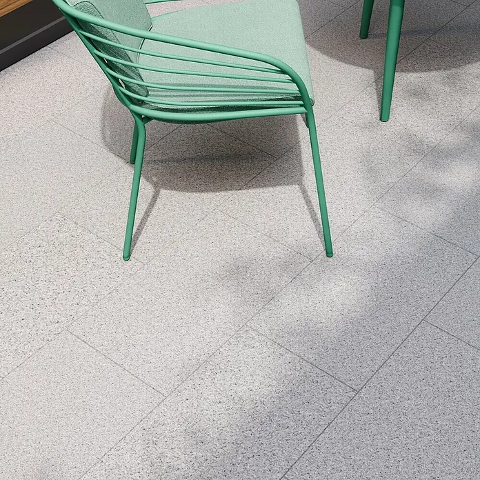Terrassenplatte G 603 - 60 x 40 x 3 cm, Grau, Granit - Detailaufnahme eines mintgrünen Stuhls auf einem gefliesten Boden, der das moderne Design und die Farbgebung hervorhebt.