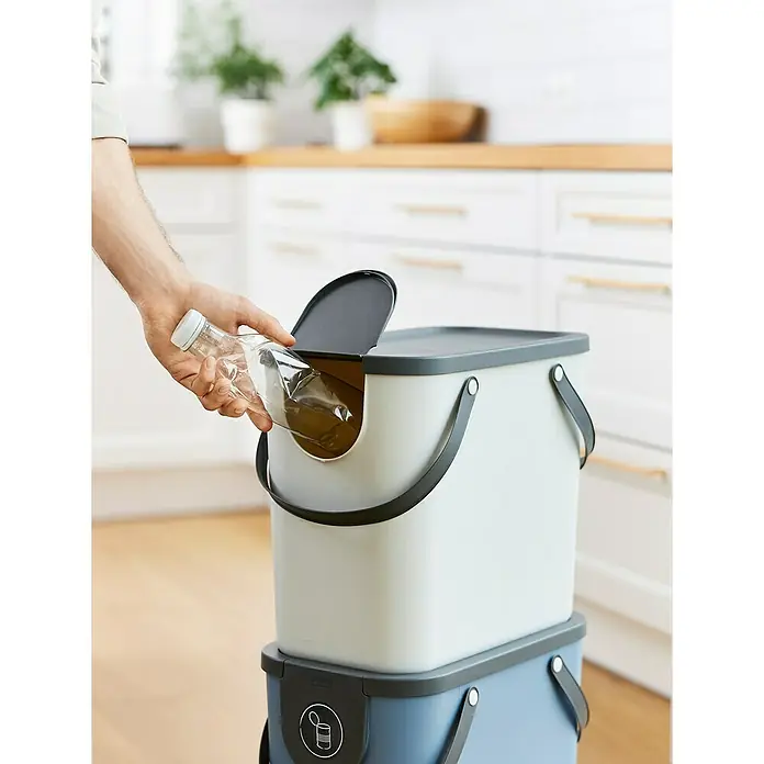 Rotho Albula Mülltrennsystem - 25 l, Kunststoff, Weiß - Ein Mülltrennsystem im Küchenbereich, in das eine durchsichtige Flasche geworfen wird. Es besteht aus zwei übereinander gestapelten Behältern.