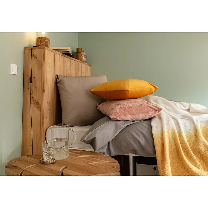 Voltomat Mono Wechselschalter mit Rahmen - Alpinweiß, Unterputzmontage, 10 A - Gemütliches Schlafzimmer-Arrangement mit Holzbett, Kissen in Gold und Rosa sowie einem Beistelltisch mit Getränken. Elegante Nachtszene.