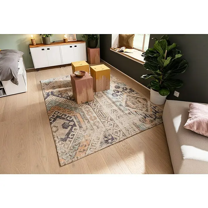 SCHÖNER WOHNEN-Farbe Naturell Wandfarbe Kreidefarbe - Blütenzauber - warmes Gelb, Matt, 2,5 l, Konservierungsmittelfrei - Ein rechteckiger Teppich mit geometrischen Mustern in Beige, Blau und Orange liegt auf einem Holzboden in einem stilvollen Wohnzimmer.