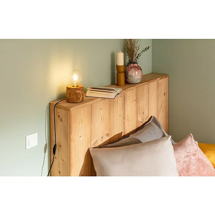 Kissen Vintage VelvetCameo Pink, 50 x 50 cm, 100 % Polyester - Das Bild zeigt ein charmantes Schlafzimmer mit einer Nachttischlampe, die ein warmes Licht verbreitet, auf einem Holzkopfteil mit Kissen.