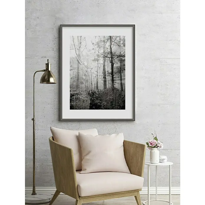 Nielsen Holzrahmen Antigo18 x 24 cm, Silber - Ein gerahmtes Kunstwerk mit Waldbild hängt an der Wand über einem Sessel mit Kissen, neben einem Beistelltisch mit Blumen.