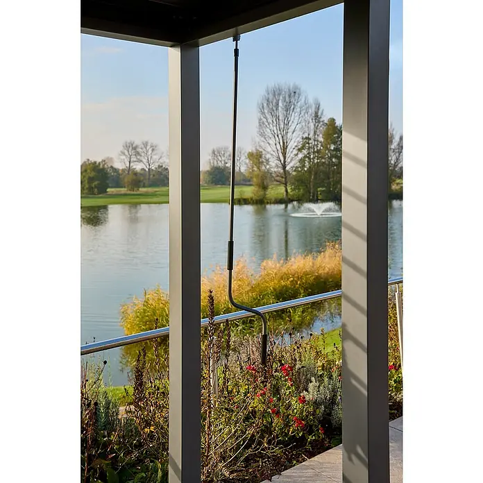 Sunfun Grillpavillon - B x T: 342 x 168 cm, Farbe Gestell: Anthrazit, Aluminium - Nahaufnahme einer Markisenkurbel vor einem See, umgeben von üppigem Grün, eingefangen durch eine architektonische Struktur.