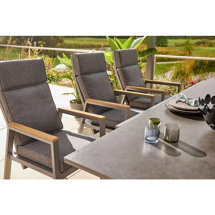 Sunfun Maja Garten-Positionssessel Deluxe - Aluminium, Polyester, Rückenlehne verstellbar, Night-Grey, B x T x H: 60 x 78 x 105 cm - Drei graue Gartensessel mit Armlehnen aus Holz stehen an einem Esstisch im Freien, perfekt für entspannte Stunden im Garten oder auf der Terrasse.