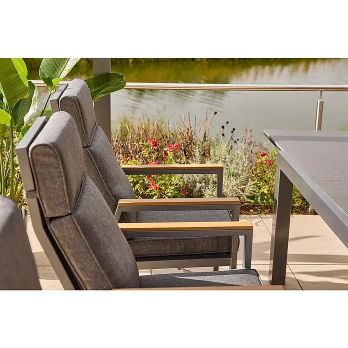 Sunfun Maja Garten-Positionssessel Deluxe - Aluminium, Polyester, Rückenlehne verstellbar, Night-Grey, B x T x H: 60 x 78 x 105 cm - Detailaufnahme von grauen Gartenstühlen mit Armlehnen und einem Tisch, die eine stilvolle und komfortable Sitzgruppe im Freien bilden.