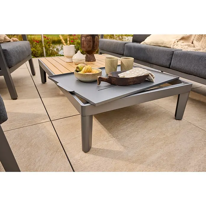 Sunfun Solo Garten-Couchtisch - L x B x H: 120 x 72 x 26 cm, Night-Grey - Ein moderner Gartentisch mit verschiebbarer Tischplatte, dekoriert mit Obst, Geschirr und Gläsern, umgeben von Gartenmöbeln.