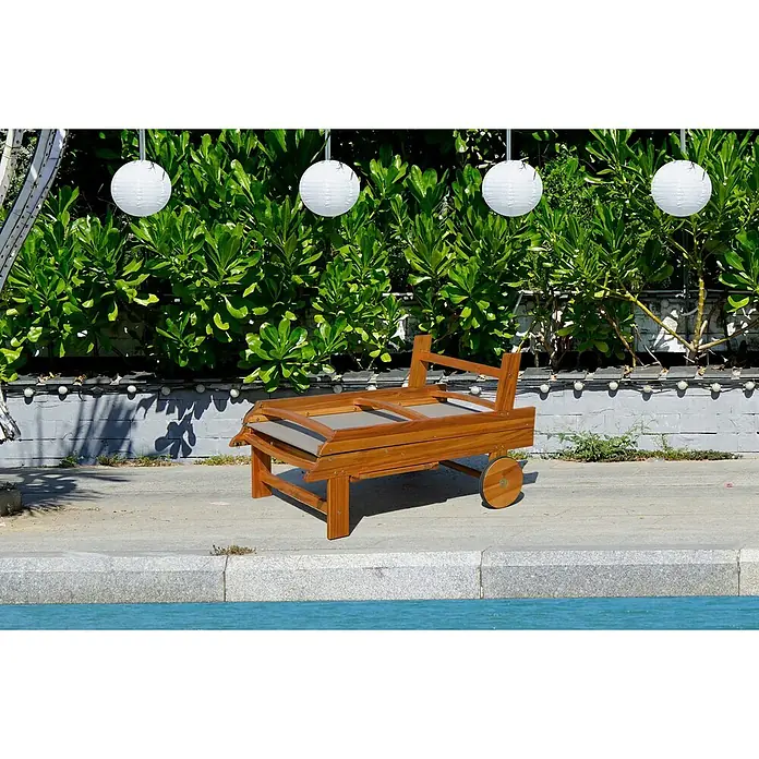Tumbona de jardín Manuela - 65 x 190 x 33 cm, Natural/Gris, Madera, Barra antivuelco - Una tumbona de playa de madera con ruedas se encuentra frente a un arbusto y luces esféricas. La tumbona está plegada.