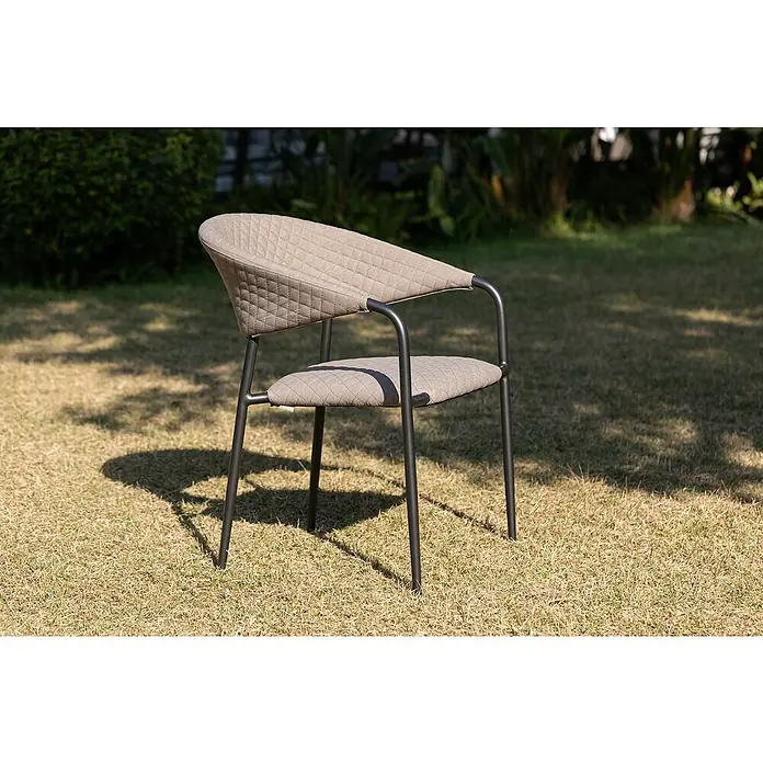 Stapelsessel - Stapelbar, Beige, B x T x H: 64,8 x 59,7 x 83 cm - Eine Nahaufnahme eines modernen, gepolsterten Stuhls mit dunklem Metallgestell, der auf einer Rasenfläche im Freien steht und Schatten wirft.