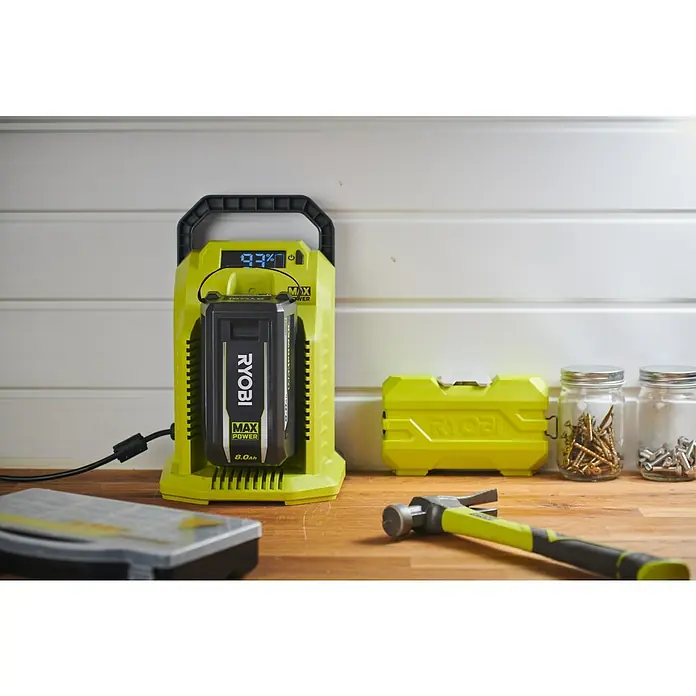 Ryobi Max Power Schnellladegerät RY36C10A - Passend für: Alle Akkus der Ryobi 36 V MaxPower-Serie - Ein Ryobi Akku-Ladegerät mit einem eingesetzten 8.0Ah Akku, das den Ladezustand von 93% anzeigt, zusammen mit Werkzeugen auf einer Werkbank.