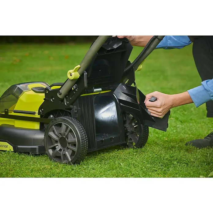 Ryobi ONE+ Akku-Rasenmäher RY18LMX40C-0 - 18 V, Ohne Akku, Schnittbreite: 40 cm - Eine Person, die den Heckauswurf-Stecker eines gelb-schwarzen Rasenmähers bedient. Der Fokus liegt auf dem Rasenmäher.