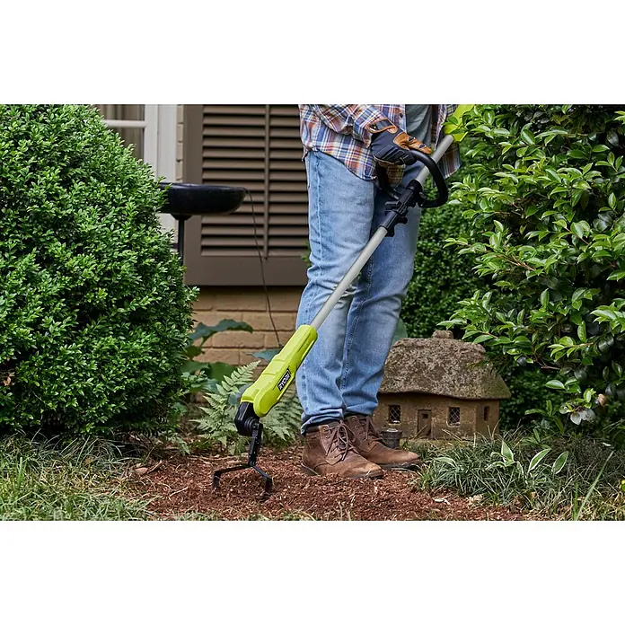 Ryobi ONE+ Akku-Bodenhacke RY18GHA - 18 V, Anzahl Akkus: Ohne Akku, Li-Ionen - Ein Mann benutzt einen Ryobi-Bodenkrümler in seinem Garten, um die Erde aufzulockern. Das Werkzeug verfügt über einen gelben Griff und einen grauen Schaft.