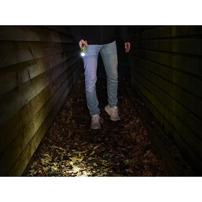Ryobi 4V USB Akku-Taschenlampe RLP4 - 4 V, 1 Akku, Lichtstrom: 640 lm - Ein Mann geht mit einer Ryobi-Taschenlampe in der Hand durch einen dunklen Gang, die das Licht auf den Weg wirft.