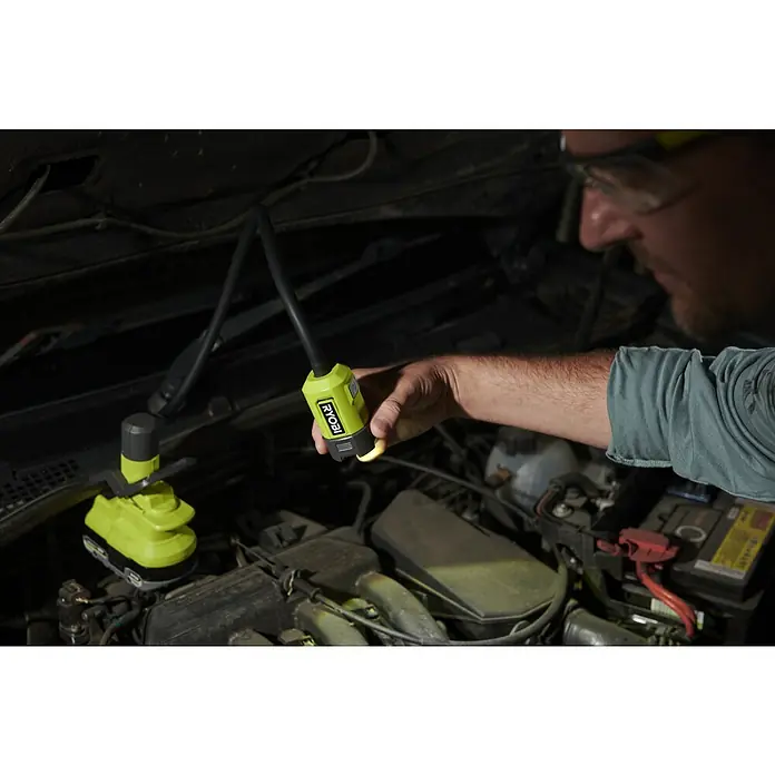 Ryobi ONE+ LED-Akkustrahler RLCF18-0 - 400 lm - Ein Mechaniker beleuchtet mit einer Ryobi Arbeitsleuchte einen Motorraum, wobei die Lampe sowohl in der Hand gehalten, als auch befestigt ist.