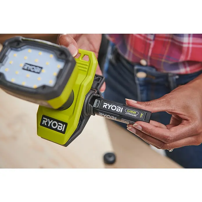 Ryobi 4V USB LED-Akkustrahler RLC4-0 - 1.000 lm - Eine RYOBI USB Lithium Arbeitsleuchte mit einem Akku, der gerade eingesetzt wird, im Fokus.