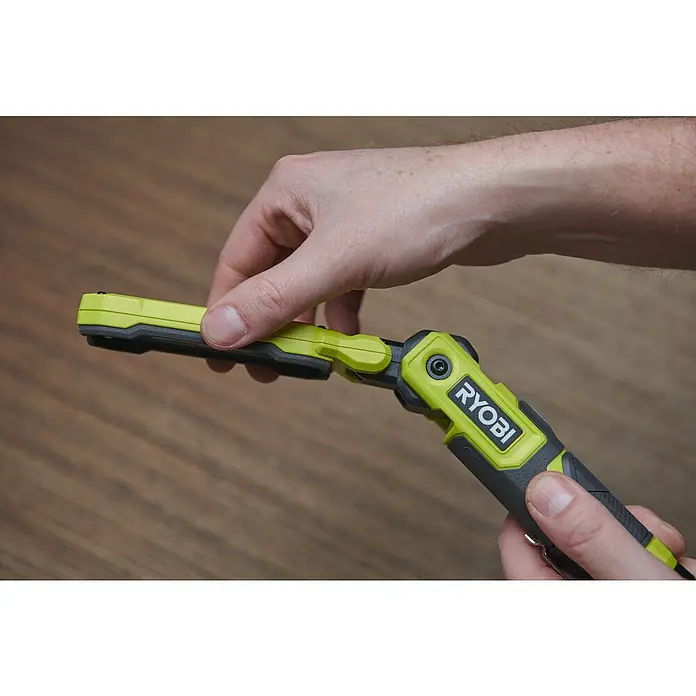 Ryobi 4V USB Akku-Stableuchte RLI4-120G - 4 V, 1 Akku, 2 Ah - Ein Mann hält eine faltbare Ryobi-Arbeitsleuchte mit grünem und schwarzem Design in der Hand, während er sie inspiziert.