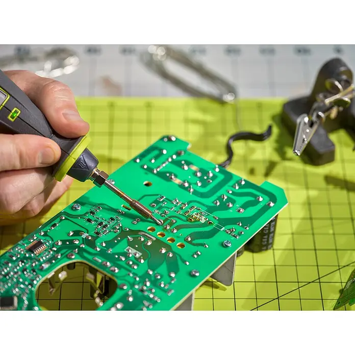 Ryobi 4V USB Akku-Lötstift RSI4-0 - 4 V, Ohne Akku - Nahaufnahme eines Lötkolbens, der auf einer grünen Leiterplatte arbeitet und feine elektronische Reparaturen durchführt.