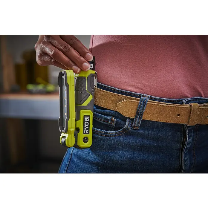 Ryobi 4V USB Akku-Stableuchte RLI4-120G - 4 V, 1 Akku, 2 Ah - Nahaufnahme einer Person mit einer Ryobi-Arbeitsleuchte am Gürtel, die die Hände frei hat.