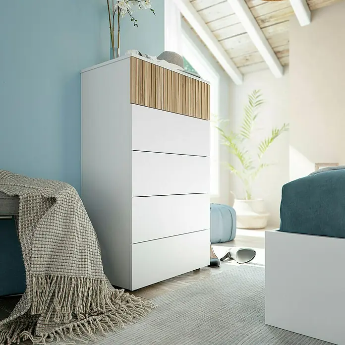 Cómoda Ethna - L x An x Al: 40 x 61 x 109 cm, Blanco Artik/Roble Natur, Número de cajones: 5 ud. - Una cómoda moderna blanca con cuatro cajones y detalles de madera en el cajón superior, situada en un dormitorio.