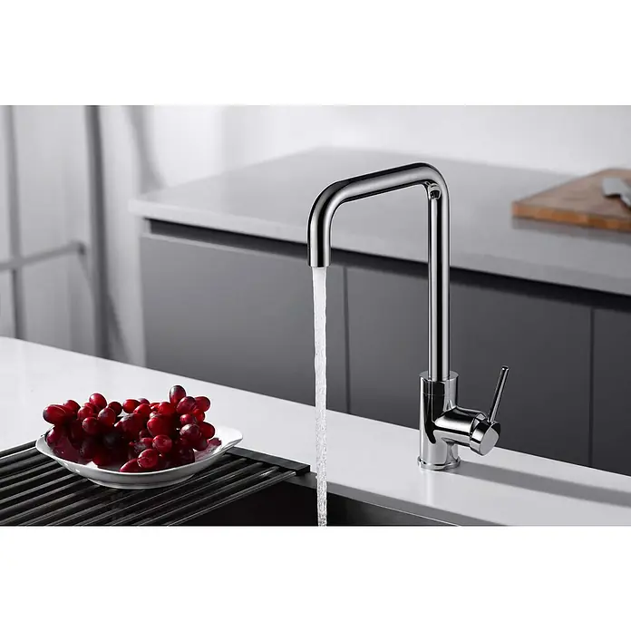 Imex Grifo de cocina Loira - Cromo - Un moderno grifo cromado cuadrado con agua corriente, situado junto a un cuenco de uvas rojas.