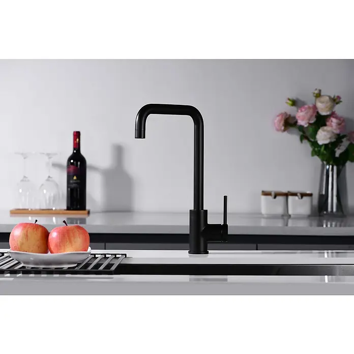 Imex Grifo de cocina Loira - Negro - Imagen de un moderno grifo de cocina negro sobre un fondo blanco y limpio. Elementos decorativos como manzanas, vino y flores complementan la escena.