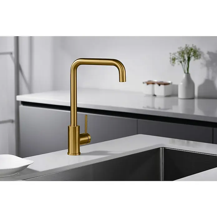 Imex Grifo de cocina Loira - Oro - Grifo de cocina dorado de acero inoxidable, con líneas limpias y modernas. Elegante accesorio sobre una encimera blanca junto a un fregadero.