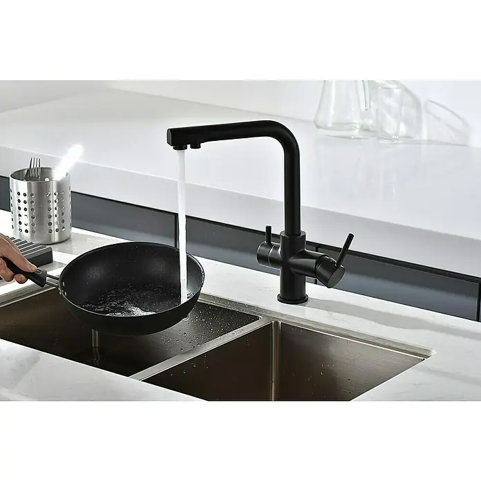 Imex Grifo de cocina ósmosis Marsella - Negro - Grifo negro sobre un fregadero de acero inoxidable, con una persona que sostiene una sartén debajo. Un diseño atemporal para cualquier cocina moderna.