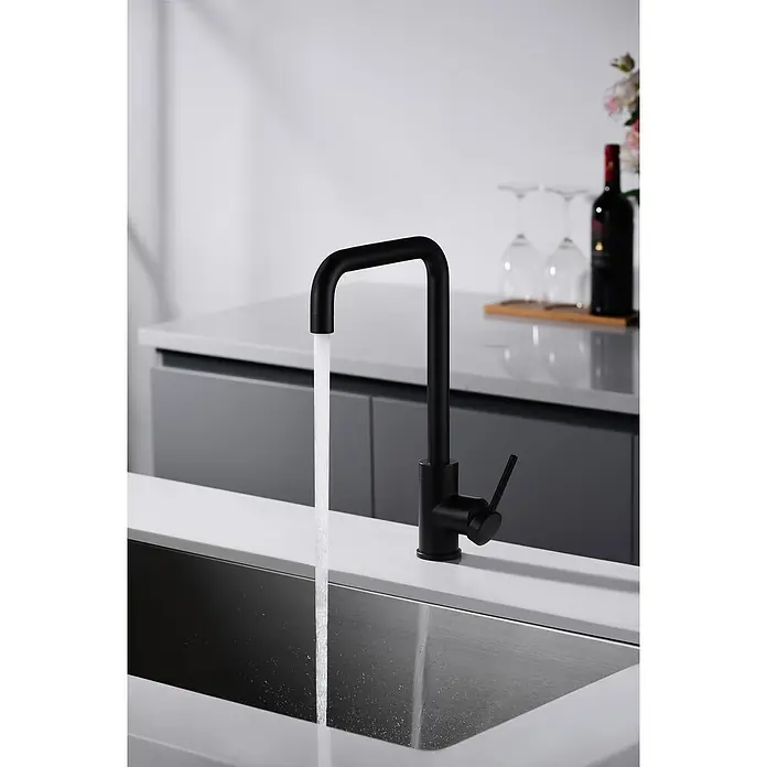 Imex Grifo de cocina Loira - Negro - Primer plano de un grifo de cocina moderno en negro mate con agua que fluye hacia un fregadero de acero inoxidable, destacando su diseño minimalista.