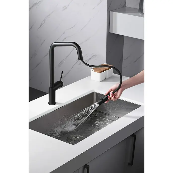 Imex Grifo de cocina extraíble Bonn - Negro - Primer plano de un grifo de cocina negro con pulverizador extraíble, rociando agua en un fregadero.