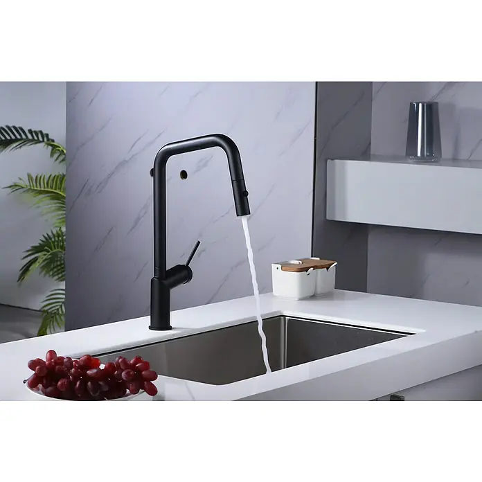Imex Grifo de cocina extraíble Bonn - Negro - Grifo negro moderno con agua corriente en un fregadero elegante, complementado con un cuenco de uvas rojas y elementos de decoración.