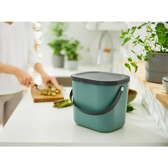 Rotho Albula Mülltrennsystem - 6 l, Kunststoff, Mistletoe Grün - Nahaufnahme eines mintgrünen Bio-Abfalleimers mit dunkelgrauem Deckel und Griff auf einer weißen Küchentheke.