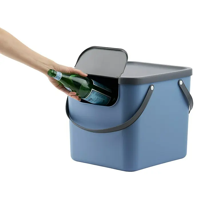 Rotho Albula Mülltrennsystem - 40 l, Kunststoff, Horizont Blau - Eine Hand wirft eine grüne Flasche in einen blauen Abfallbehälter mit grauem Deckel.
