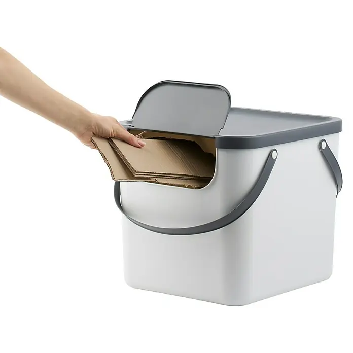 Rotho Albula Mülltrennsystem - 40 l, Kunststoff, Weiß - Eine Hand legt Kartons in einen grauen und weißen Recycling-Behälter mit Deckel. Umweltfreundliche Abfallentsorgung leicht gemacht.