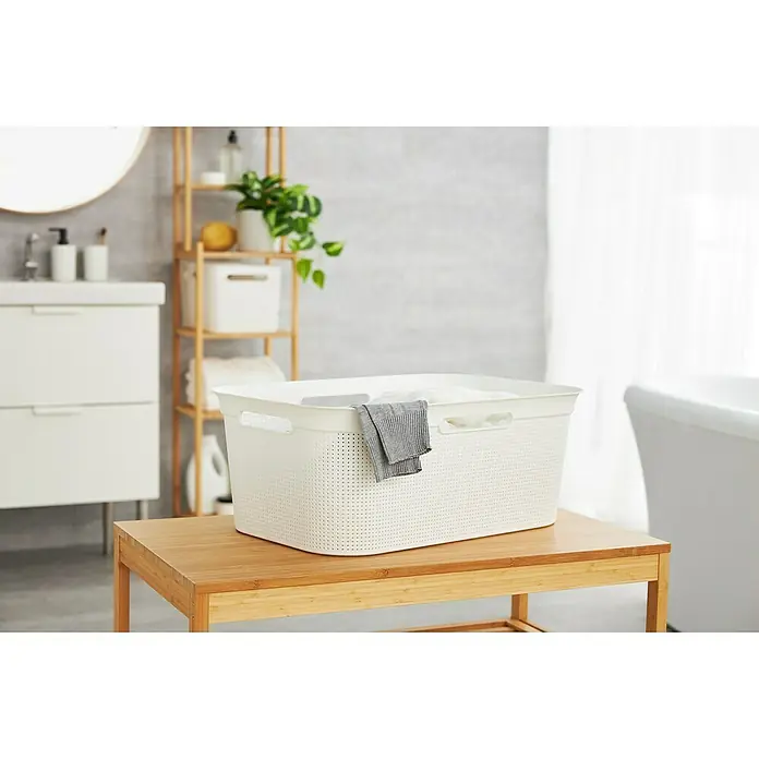 Rotho Wäschekorb Brisen - L x B x H: 59,6 x 39,6 x 23,2 cm, Kunststoff, Weiß - Ein weißer Wäschekorb aus Kunststoff steht auf einem Bambushocker im Badezimmer. Ideal für die Aufbewahrung von Schmutzwäsche.