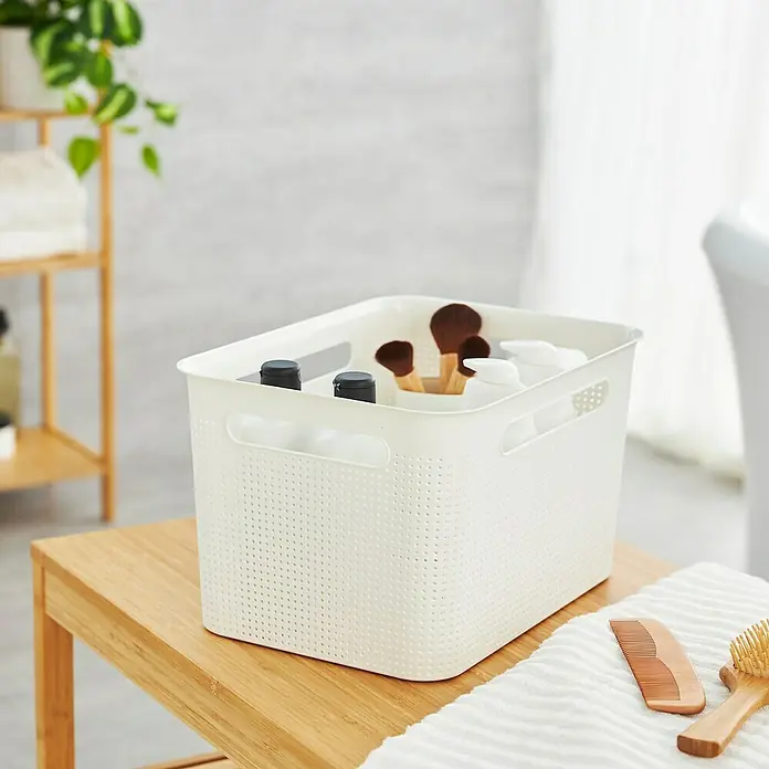 Rotho Aufbewahrungsbox Brisen - L x B x H: 36 x 26,2 x 21,1 cm, Kunststoff, Weiß - Ein weißer Aufbewahrungskorb aus Kunststoff auf einem Holztisch im Badezimmer. Ideal für Kosmetik, Bürsten und Flaschen.