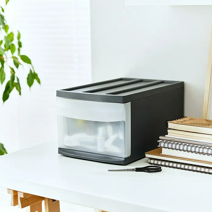 Rotho Schubladenbox Systemix M - L x B x H: 39,5 x 25,5 x 20,3 cm, Anthrazit, Anzahl Schubladen: 1 Stk. - Schubladenbox auf einem Schreibtisch mit Notizbüchern und einer Schere daneben.