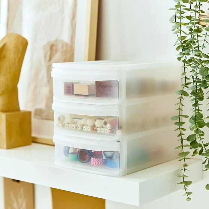 Rotho Schubladenbox Systemix Tower - L x B x H: 26,5 x 19,2 x 23,3 cm, Transparent, Anzahl Schubladen: 3 Stk. - Ein übersichtlicher Organizer mit drei durchsichtigen Schubladen zur Aufbewahrung von Büro- und Bastelbedarf auf einem weißen Regal.