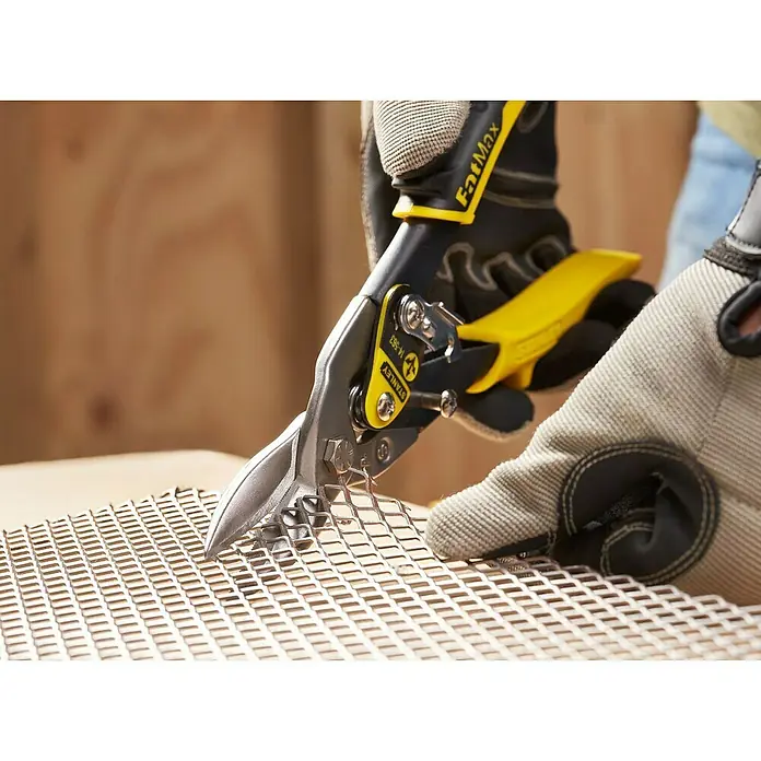 Stanley FatMax Blechschere - Länge: 250 mm, Schnittlänge: 1,2 mm, Gerade - Nahaufnahme einer Hand, die mit einer Stanley Blechschere ein Metallgitter schneidet. Die Schere hat gelbe Griffe und ist mit "FatMax" gekennzeichnet.