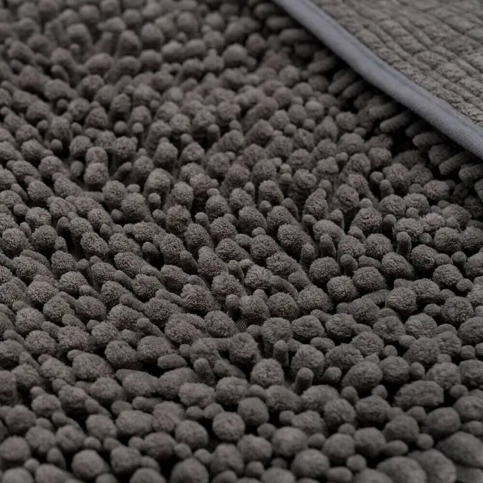 Camargue Badteppich Fluffy - 50 x 90 cm, Grau, 100% Polyester - Nahaufnahme eines grauen, zotteligen Teppichs mit einem schlichten, grauen Rand. Der Teppich bietet eine weiche, strukturierte Oberfläche.