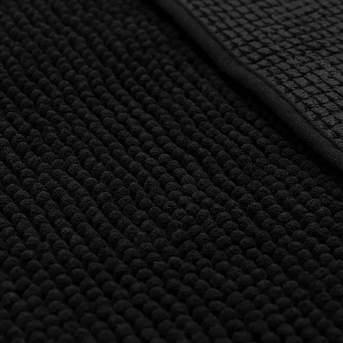 Camargue Badteppich Zottel - 50 x 80 cm, Schwarz, 100% Polyester - Nahaufnahme einer schwarzen Badematte mit Noppenstruktur und einem Rand mit quadratischem Muster, die Textur und Design hervorhebt.