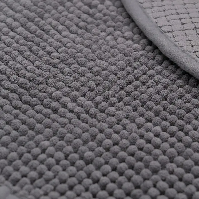 Camargue Badteppich Zottelino - 55 x 55 cm, Grau, 100% Polyester - Detailaufnahme einer grauen Badematte mit Noppenstruktur und abgesetztem Rand, die für Komfort und Sicherheit im Badezimmer sorgt.
